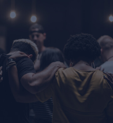 people gathered in a circle arm in arm